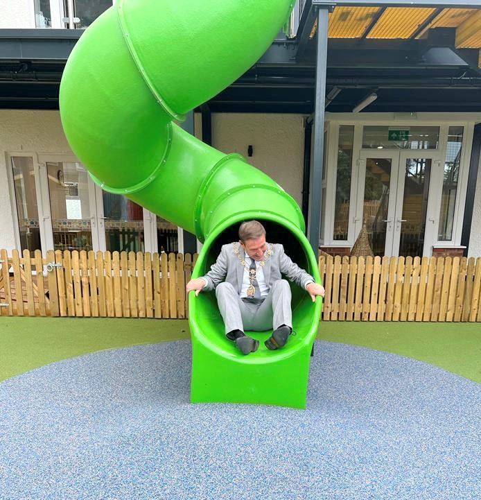 A Mayor going down a children's slide