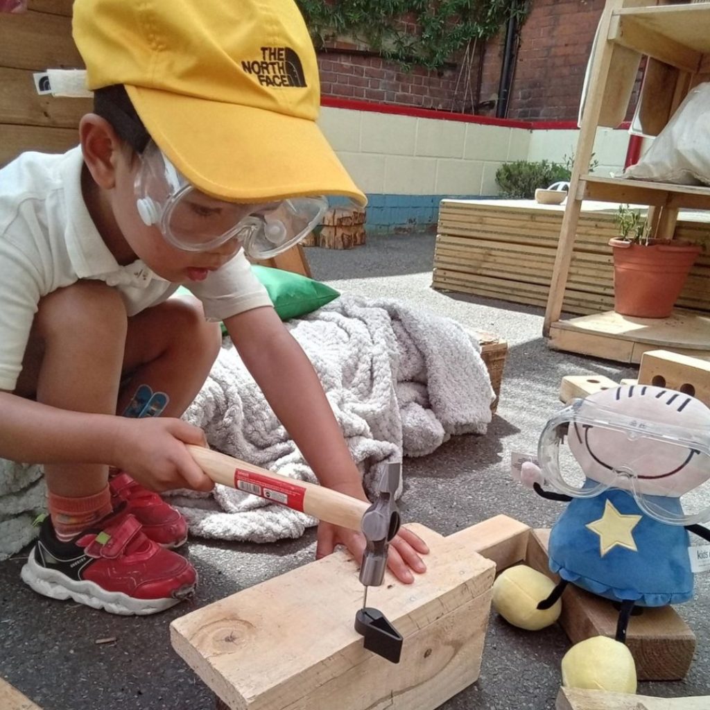 Health & Safety Star Doll with child doing woodwork at one of our nurseries.